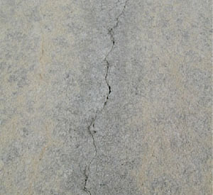 Close-up photo of a single tight crack in a PCC slab. The crack has no visible spalling.