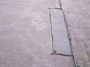 Overview photo of a transverse joint with a small rectangular PCC patch along the joint on one of the slabs.           The patch is in very good condition with no visible signs of distress.
